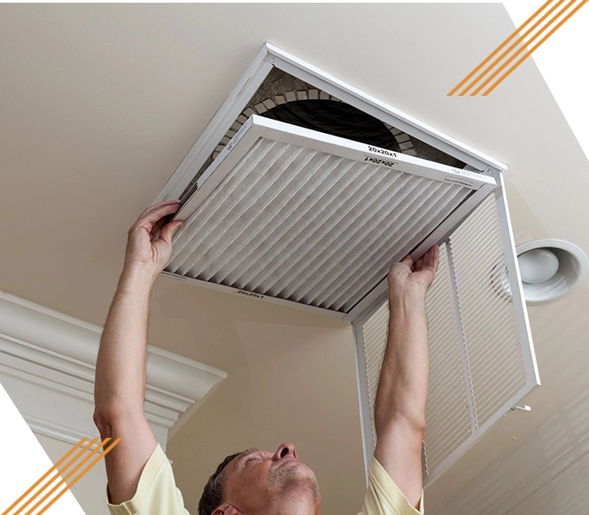 A man is holding an air filter up to the ceiling.