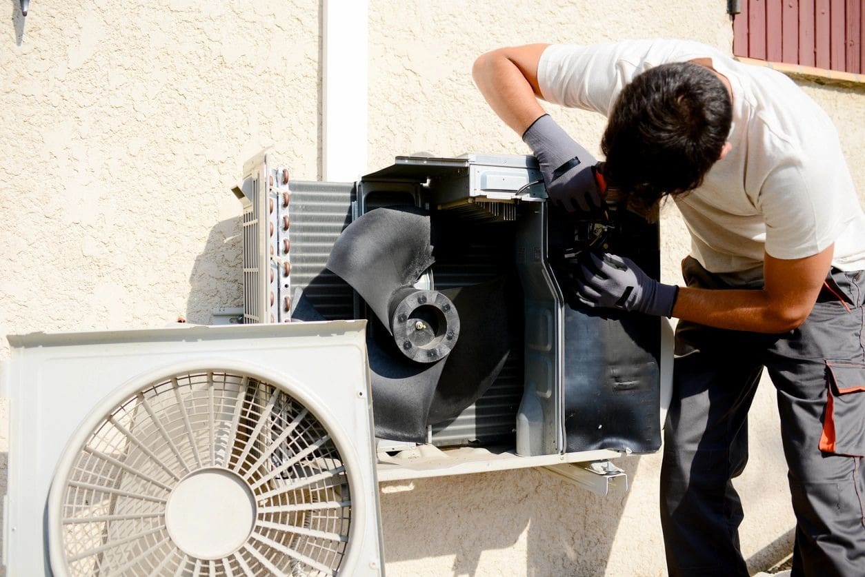 A man working on an air conditioner outside.