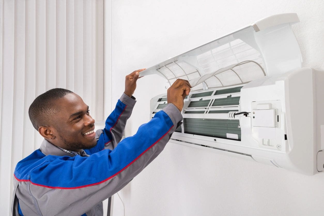 A man is fixing the air conditioner on his wall.