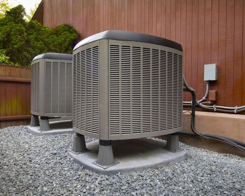 Two air conditioners are sitting on the ground.