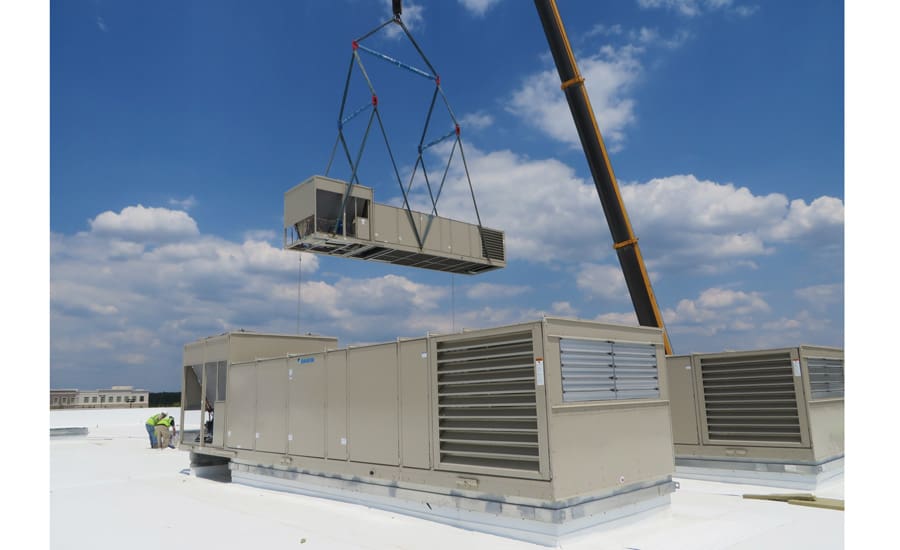 A crane is lifting an air conditioner unit.